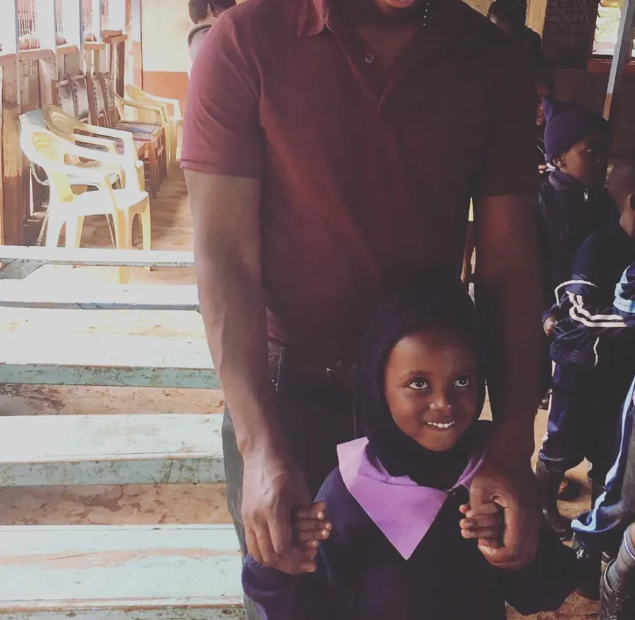 A smiling child holding an adult’s hands, supported through educational work with Verdant