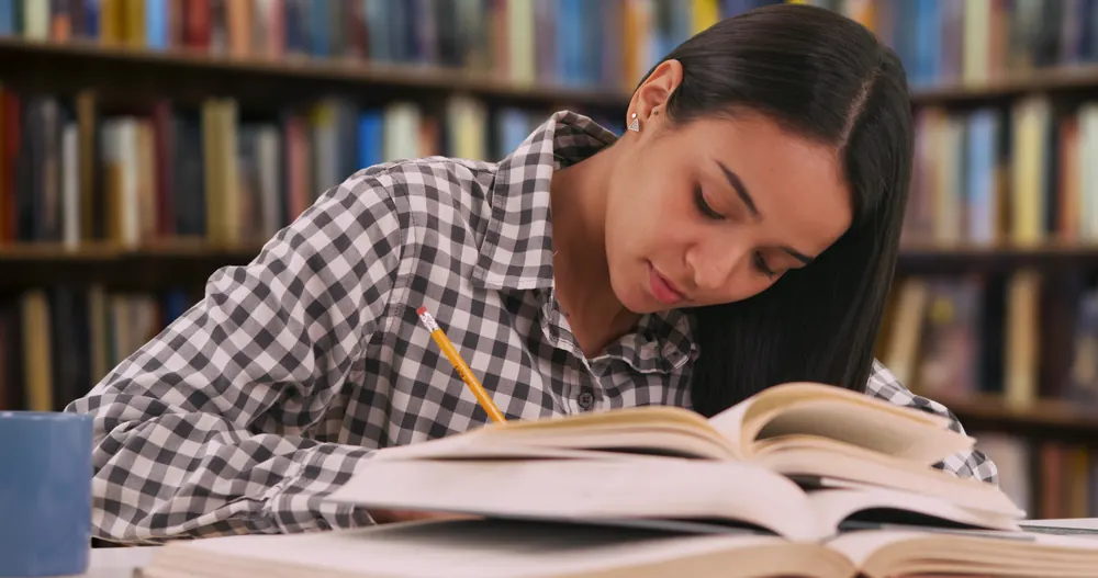A student studying with open books in a library