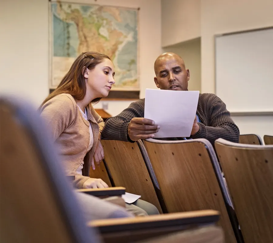 A tutor and a student reviewing work together in a lecture room